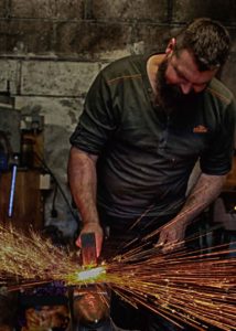 Blacksmith Jim in his forge hitting steel creating a shower of sparks